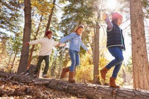 Kinder balancieren im Wald auf Baumstamm schulreif im Waldkindergarten