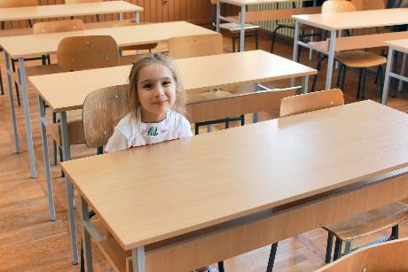 Eine Schülerin sitzt in einem leeren Klassenzimmer