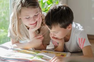 Ein Mädchen und ein Junge lesen gemeinsam ein Buch - jahrgangsübergreifendes Lernen