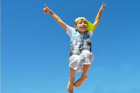 Glückliches Kind voller Selbstbewusstsein jubelt beim Hüpfen
