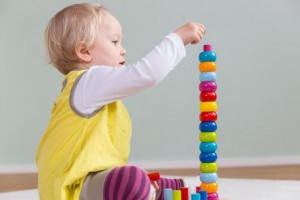 Kleinkind spielt mit Bauklötzen konzentriert allein Pikler
