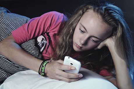 Kind mit Smartphone Handy im Bett