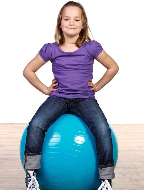 Ein Mädchen sitzt auf einem Gymnastikball Sitzball