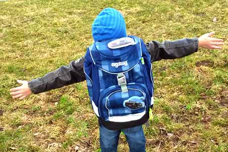 Junge glücklich mit ergobag-Schulranzen Schulrucksack auf seinem Rücken