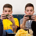 Kinder und Jugendliche zocken gerne piele-Apps - Zwei Jungen mit Smartphone auf der Couch