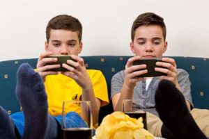 Kinder und Jugendliche zocken gerne piele-Apps - Zwei Jungen mit Smartphone auf der Couch
