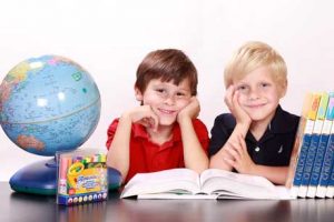 Gesundes Lernen macht Spaß - zwei Jungen mit Globus und Büchern schauen glücklich
