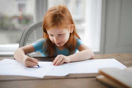 Kleines Mädchen lernt fleißig und füllt Arbeitsblätter nach Montessori-Pädagogik aus